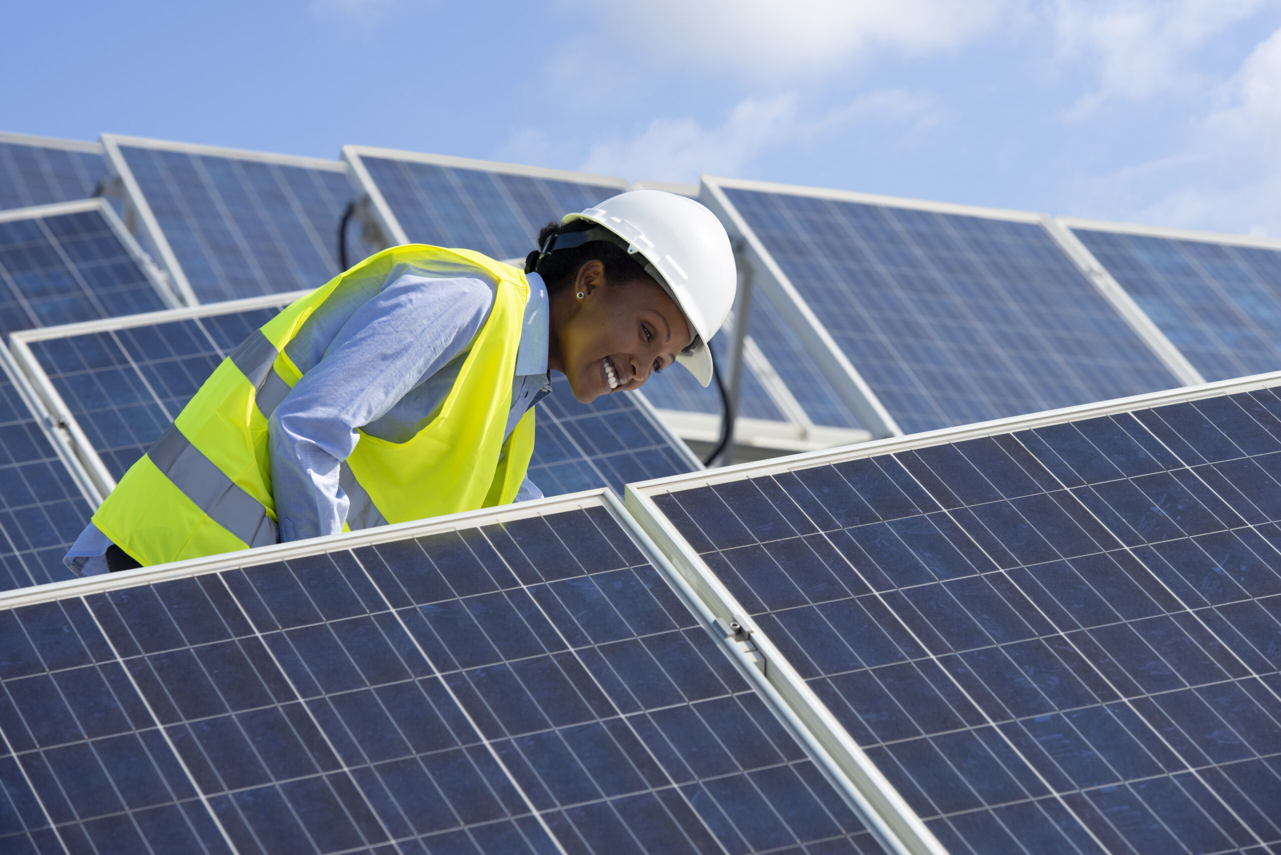 Energy engineer woman working on a roof with solar panels.