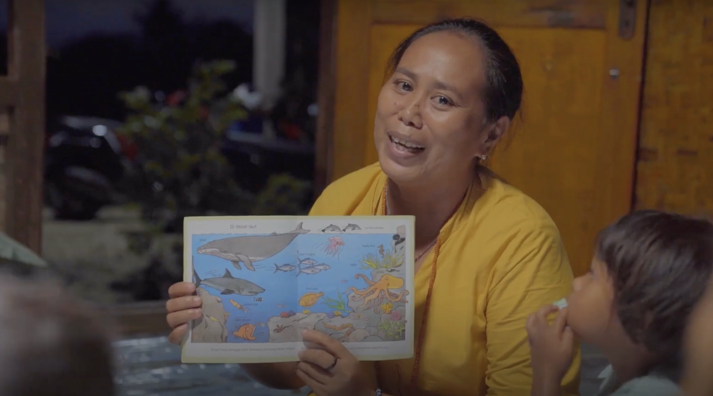 Woman holds a map in front of a group of children.