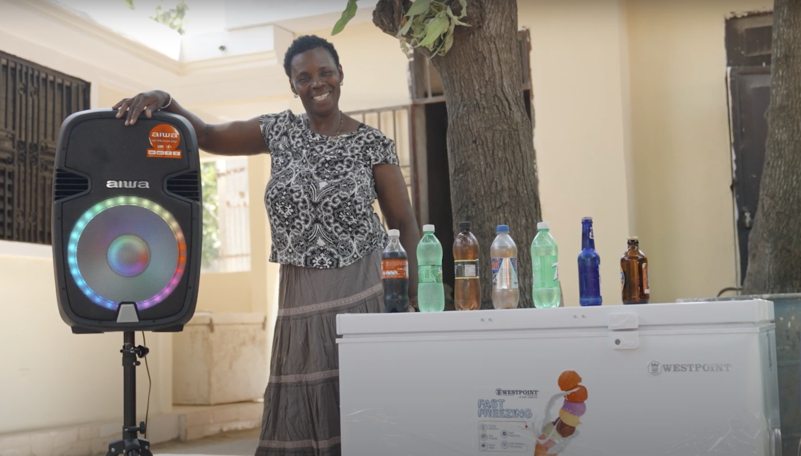 Woman poses by speaker and refrigerator powered by green energy