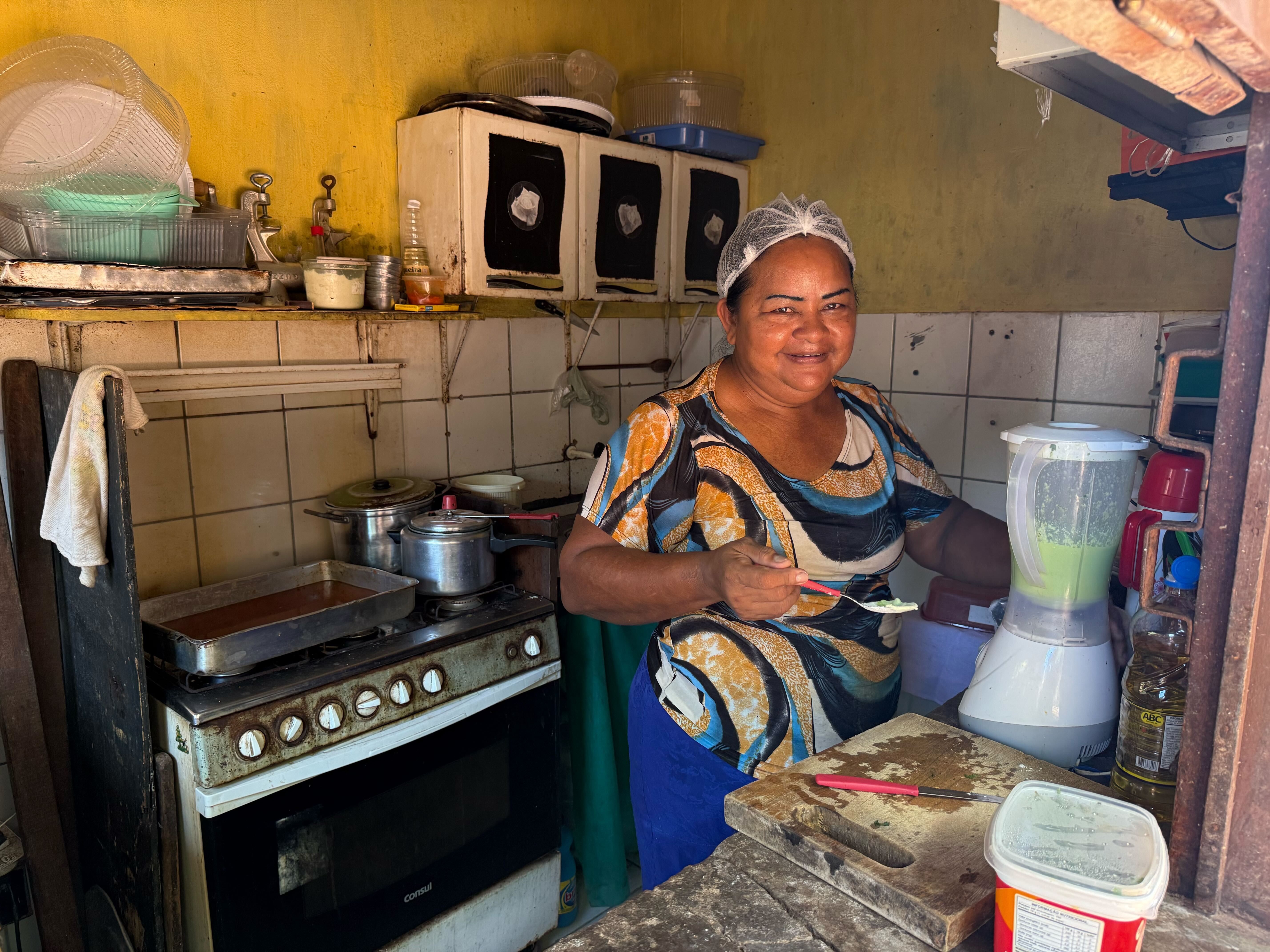 A female entrepreneur smiling at the camera while working in her kitchen.
